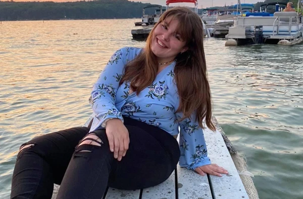 A young woman sitting on the edge of a boat dock.